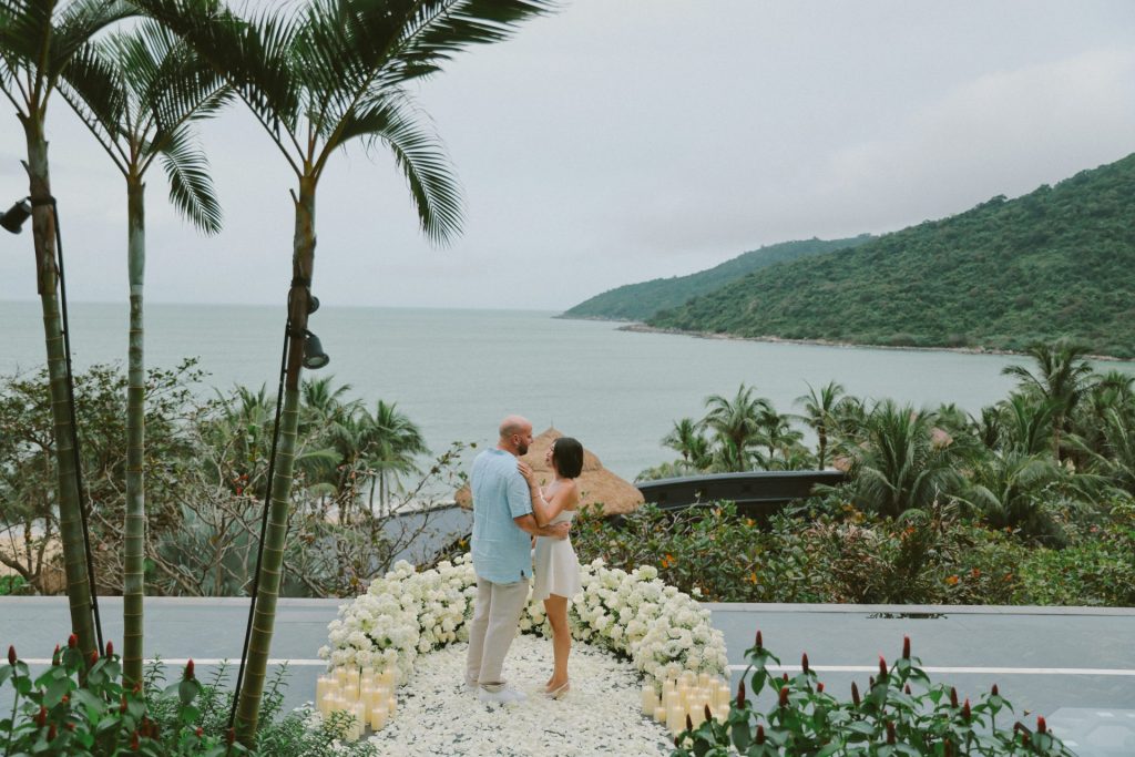 Pareja bailando junto al mar con palmeras.